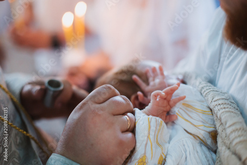 Close-up of a baby's hands during a baptism ceremony.