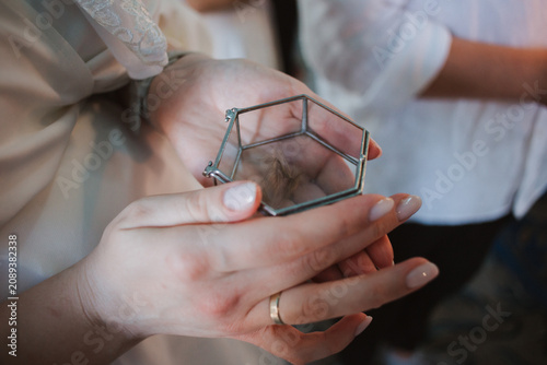 A glass box with a child's hair in the hands of the godfather.