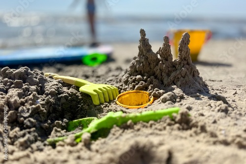 Foto A charming sandcastle construction on a sunny beach, surrounded by colorful plastic toys like rakes and buckets