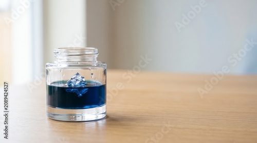 Small inkwell with a miniature iceberg floating inside, concept of hidden depths and the tip of the iceberg