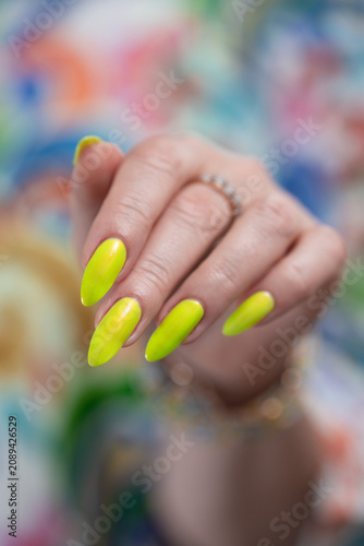 Konstfotografi Female hand with long nails and neon yellow green manicure