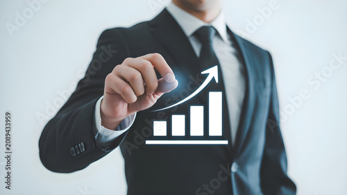 Businessman in formal dark suit pointing at virtual digital growth chart representing financial success and corporate development in modern workplace.