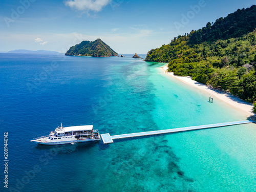 Foto Aerial drone view of tropical landscape over Madam Beach of Nyaung Oo Phee Island with tour boat anchoring on the floating dock in the Mergui Archipelago, Myanmar
