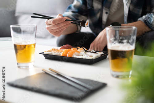 Man eating sushi with chopsticks at home