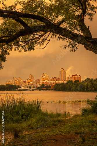 Dramatic sunset after a thunderstorm over Obolon Embankment in Kyiv, Ukraine. Sun light break through storm clouds, reflecting across the Dnipro River and city skyline.

