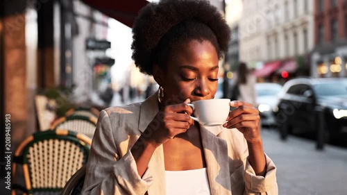 Smiling Black woman enjoying coffee at urban outdoor cafe