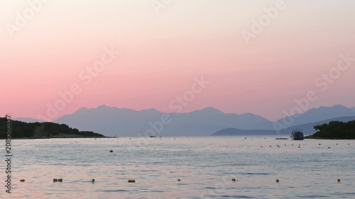 Sunset over the Albanian Riviera with calm sea and mountain silhouette