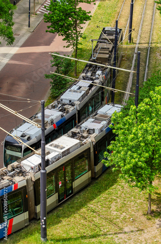 Rotterdam, The Netherlands, May 31, 2026: aerial view of two trams passing on their tracks surrounded by greenery