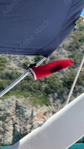 Albanian flag attached to a motorboat, waving in the wind with rocky cliffs in the background