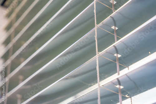 Close up of aluminum window blinds with tilt mechanism and slats. Sunlight regulation and privacy protection concept for modern buildings
