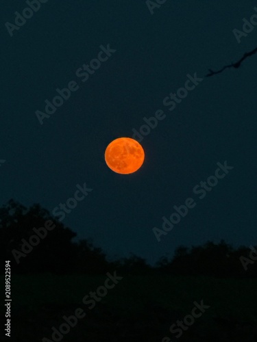 Beautiful full Strawberry Moon glowing above a peaceful night landscape under a dramatic sky. Atmospheric celestial scene featuring the famous June full moon, perfect for astronomy, nature, and nightt