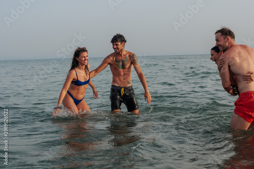 Принти на полотні Friends laughing splashing in ocean water enjoying summer vacation