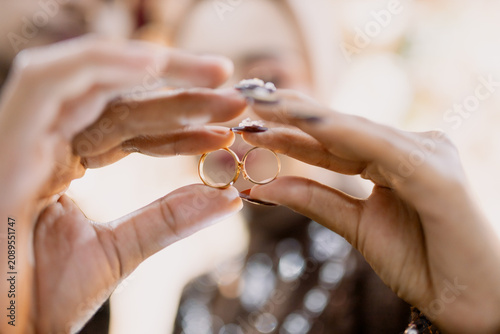 Two hands holding golden wedding rings in elegant gesture