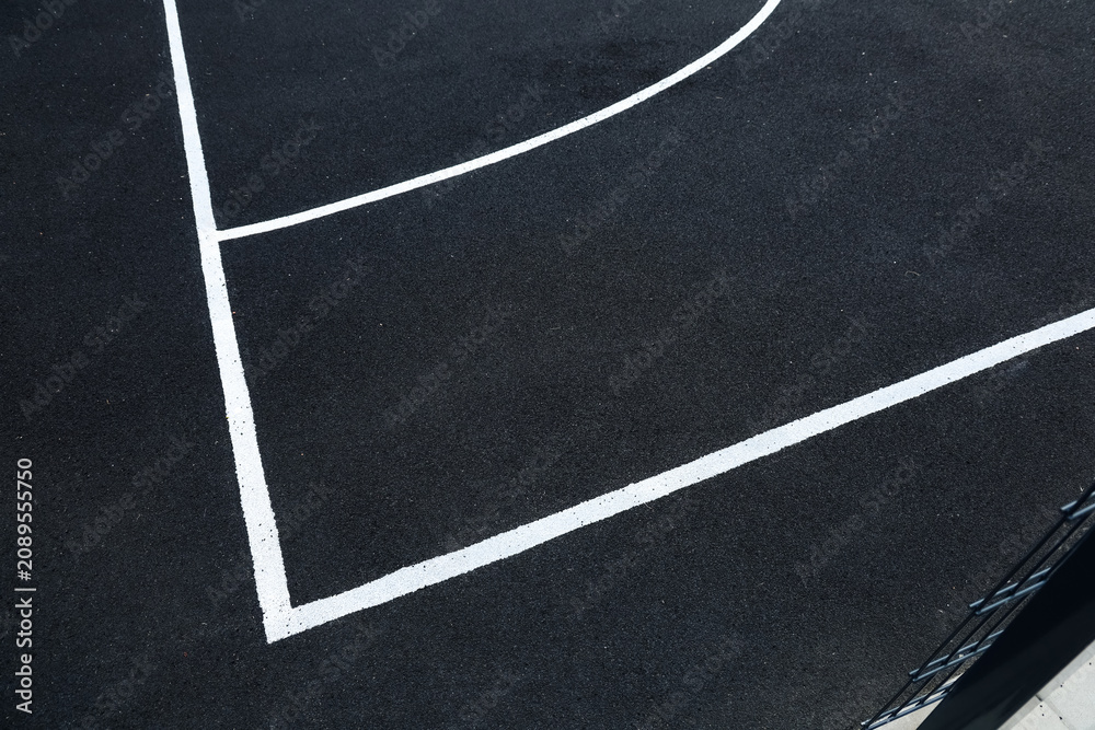 Fototapeta premium Basketball court lines are marked on a black surface showing a clear outline of the court area