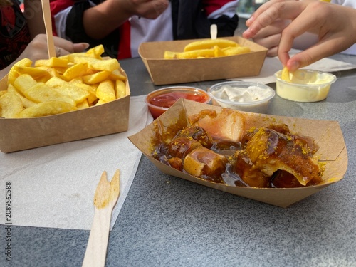 Currywurst mit Pommes Frites auf einem Streetfood-Festival in der Düsseldorfer Altstadt. Beliebtes deutsches Fast Food als Editorial-Motiv für Gastronomie, Tourismus und Genuss.