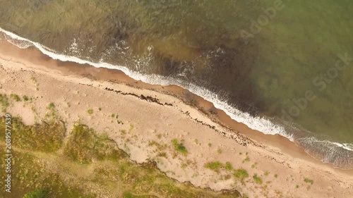 Aerial top down view of a sandy beach with crashing waves