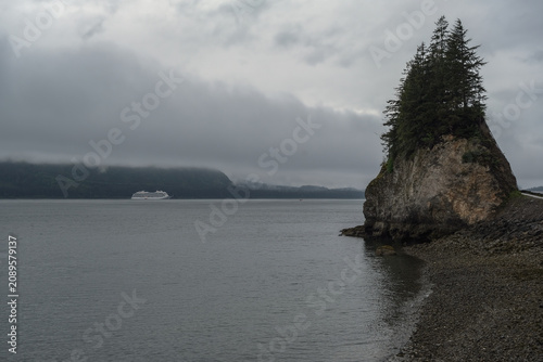 Breathtaking and impressive panoramic scenic view of Icy Strait Point Hoonah, AK coast with lush mountain vegetation and trees during summer Last Frontier cruise with distant mountain range glaciers