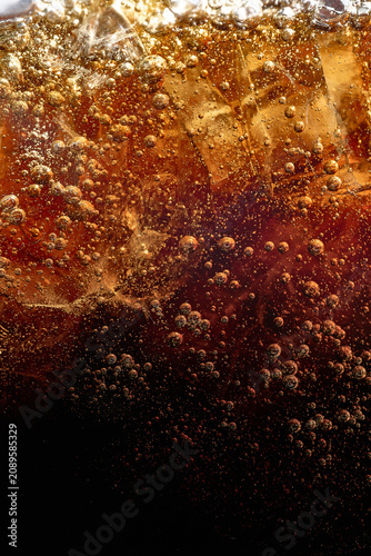 Canvas Print Dark carbonated beverage with ice bubbles and amber splash