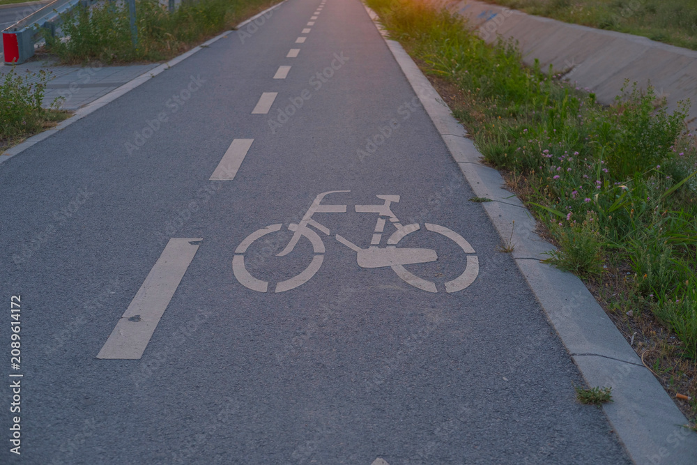 Obraz premium Bike lane marking on asphalt road with bicycle symbol and white lane lines for cycling infrastructure design