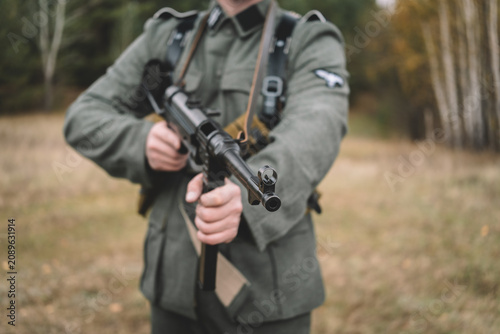 World War II German soldier holding an submachine gun in a forest. Historical military reenactment