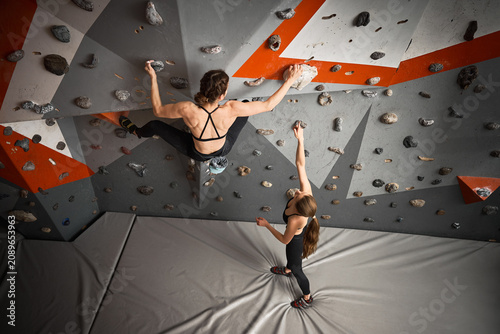 Obraz na plátne Two female climbers work on route in indoor bouldering hall