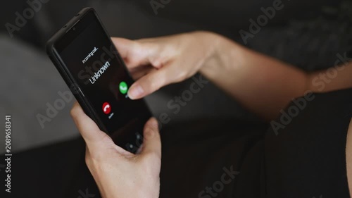 Woman holding smartphone with incoming call from unknown suspicious caller.