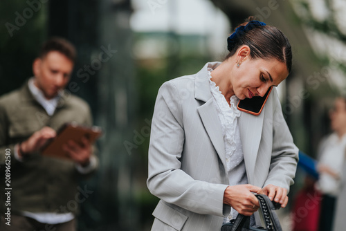 Tableau sur toile A professional woman talks on her smartphone while rummaging through her handbag