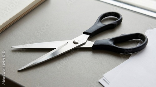 Black handled scissors on a desk with paper