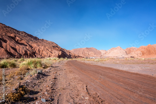 Desert dirt road weaving through red hills in the Atacama Desert in Chile