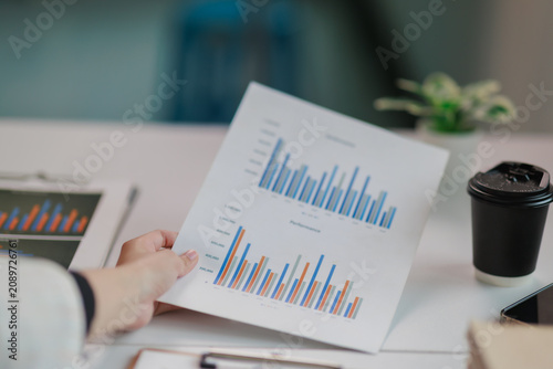 Photos Business professional holding financial document with bar graph reports, analyzi