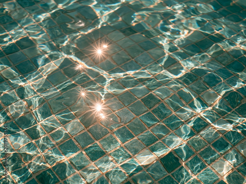 Turquoise pool mosaic tiles with sparkling sun reflections