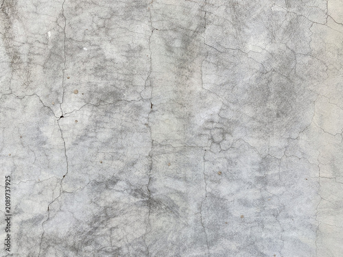 A close up view of an aged grey concrete wall with fine cracks and natural weathered texture.