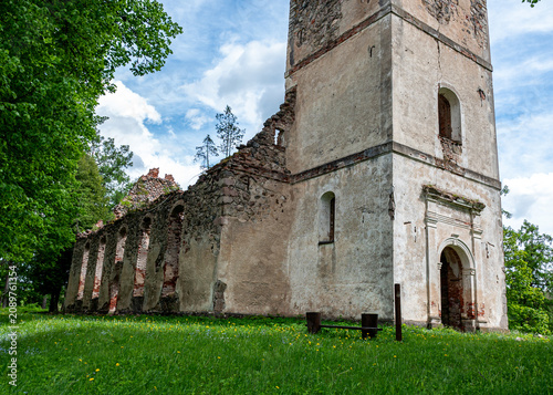 Obraz na płótnie Sunny landscape with old stone church ruins, The church was a brick building with a rectangular chancel and a protruding tower with a baroque spire