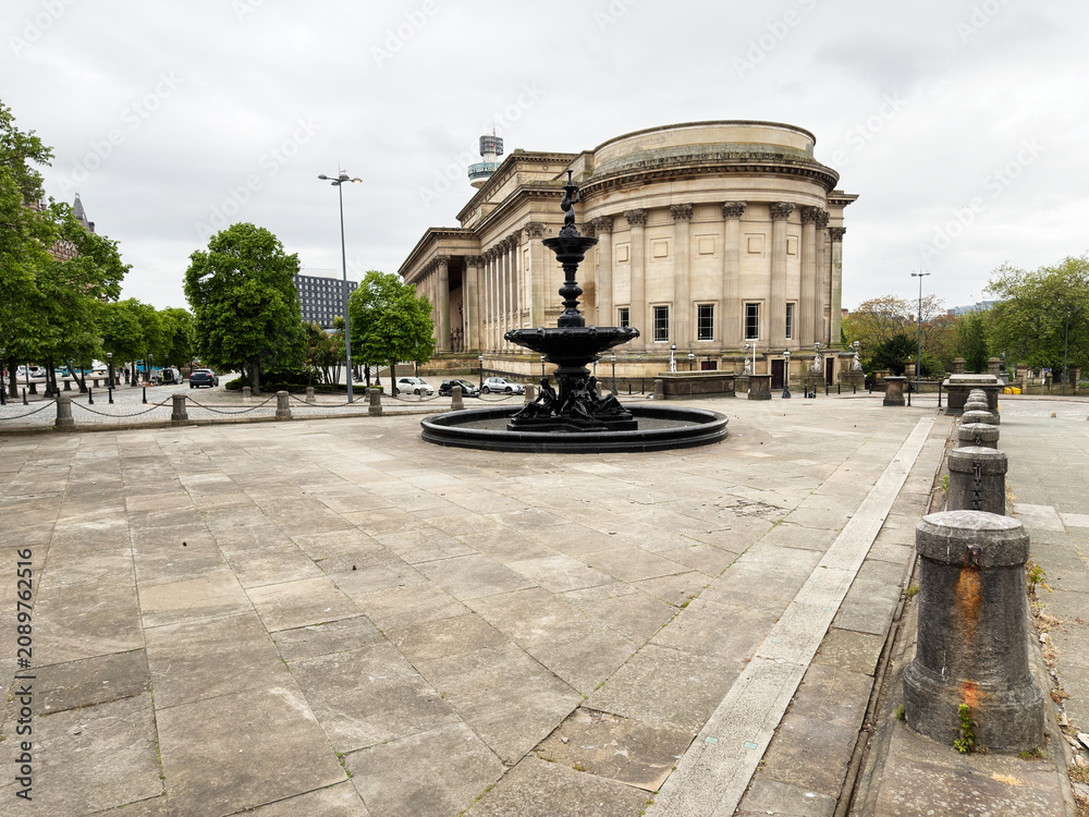 Obraz premium Neoclassical building and ornamental fountain on a wide paved plaza in Liverpool, UK under an overcast sky