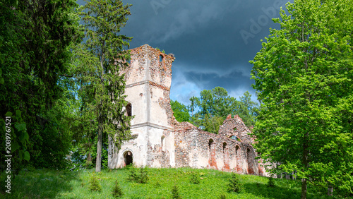 Fotografi Sunny landscape with old stone church ruins, The church was a brick building with a rectangular chancel and a protruding tower with a baroque spire
