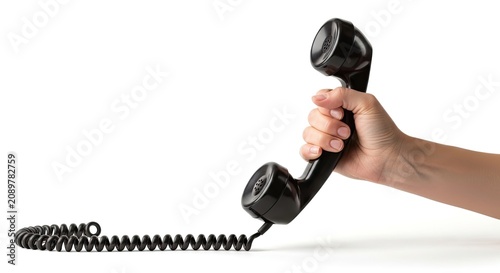 A hand holds a black rotary telephone against a white background. The telephone features a coiled cord and a black handset.