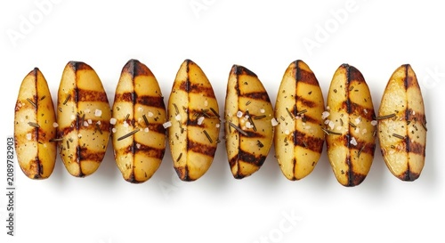 A row of grilled potato halves sits on a white surface. The potatoes are seasoned with salt and rosemary.