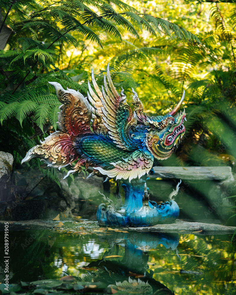Obraz premium Colorful Dragon Statue Reflecting in Pond