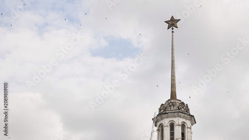 Photography Soviet star and hammer and sickle atop a historical building spire against cloudy sky in Moscow