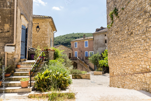Vieux village avec maisons en pierres sous le soleil, volets fermés, rues pavées désertes. Montclus dans le Gard, France