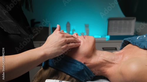 Cosmetologist's hands massaging a woman's face and neck during a professional beauty treatment