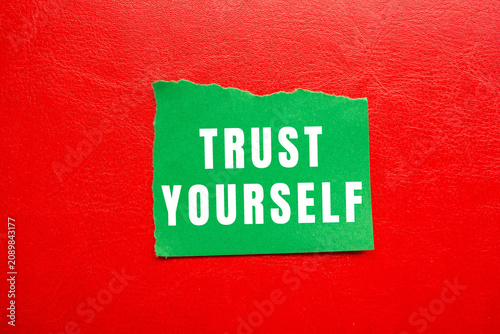 Obraz na plátně Green paper with text trust yourself against a textured red background, symboliz