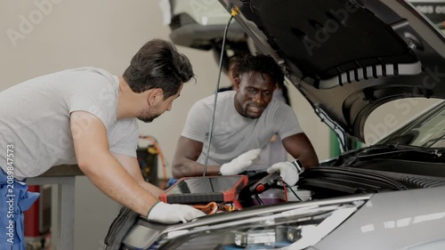 EV Car engineer team working service maintenance Electric cable in front of EV car hood checking replacing or installation