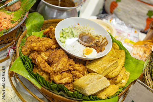 Traditional Thai rice vermicelli salad served with crispy fried chicken, tofu, boiled egg, fresh cucumber, and spicy dressing at a local street food market.