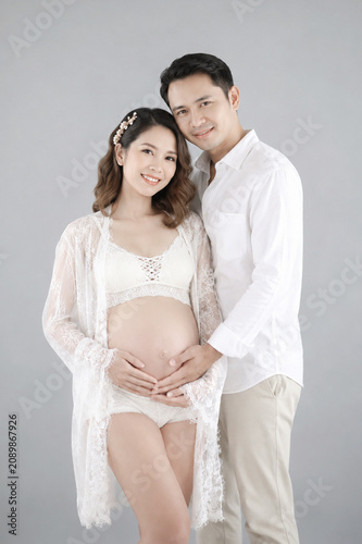 Expecting Joy: A loving couple, the expectant mother cradles her baby bump, while her partner embraces her, capturing a tender moment of anticipation and new life.