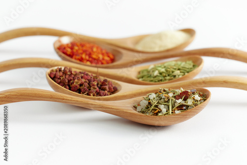 Photography Assorted seasonings and spices in wooden spoons on white background