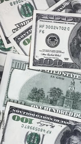 A collection of hundred-dollar bills is shown on a flat surface. The money is stacked in different ways across the frames, highlighting its details.