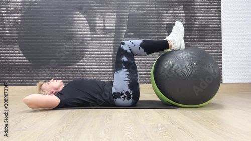A person performs core exercises with an exercise ball in a gym. The workout focuses on stability and abdominal strength.