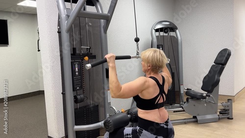 A woman performs a pull-down exercise at the gym to strengthen her back and arms. This workout focuses on proper form and technique.