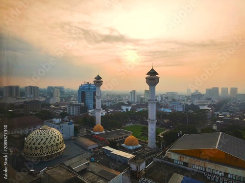 Bandung, Indonesia - July 09 2026: Aerial landscape view of the Bandung Square area against the background of the twin towers of the Bandung Grand Mosque at foggy sunrise.